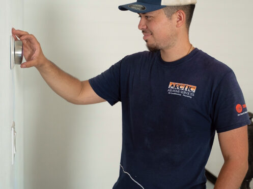 Arctic Air technician adjusting a thermostat