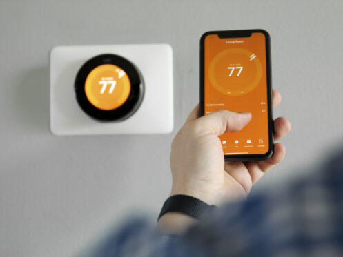 Man uses a mobile phone with smart home app in modern living room